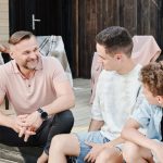 Family sharing quality time on a wooden terrace. Smiling and conversing.